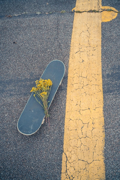 Hooghoekbeeld van skateboard met bloemen op de weg