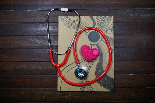 Foto hooghoekbeeld van stethoscoop met hartvorm en boek op houten tafel