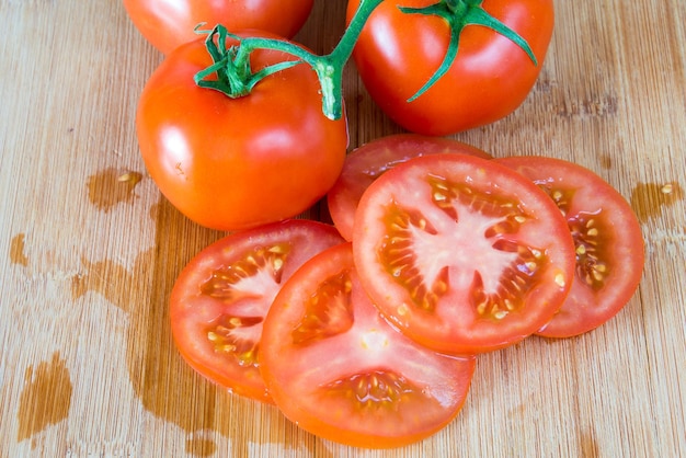 Hooghoekbeeld van tomaten en hun plakjes op de snijplank