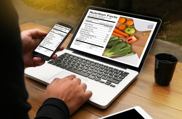 Foto hooghoekbeeld van vrouw met mobiele telefoon en laptop aan tafel