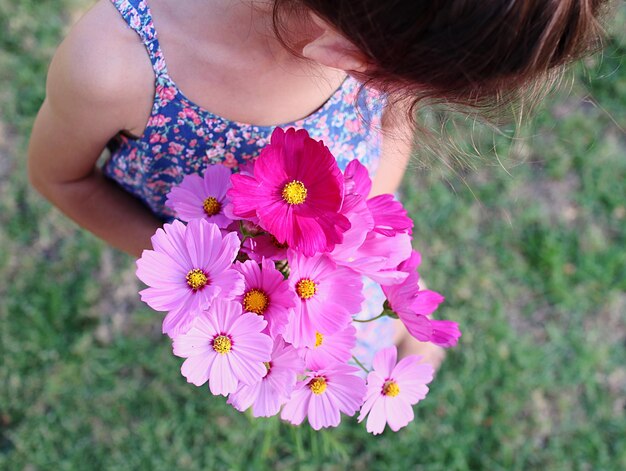 Foto hooghoekbeeld van vrouw met roze bloemen op het veld