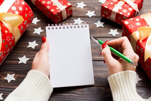 Foto hooghoekbeeld van vrouwelijke handen met boek en pen bij geschenken op tafel