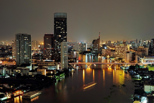 Hooghoekfoto van de rivier langs de verlichte stad