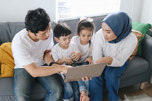 Hooghoekfoto van ouders die hun kinderen thuis leren met behulp van een laptop