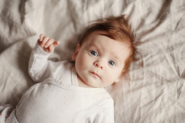 Hooghoekportret van een schattig baby meisje dat op bed ligt
