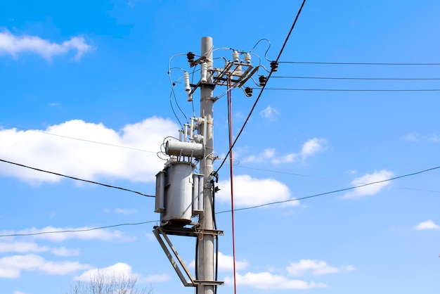 Hoogspanningsdraden en paalstroomlijnen elektrische torenspower transformator tegen levendige blauwe lucht, wolken en zon Transmissie van elektriciteit op lange afstanden