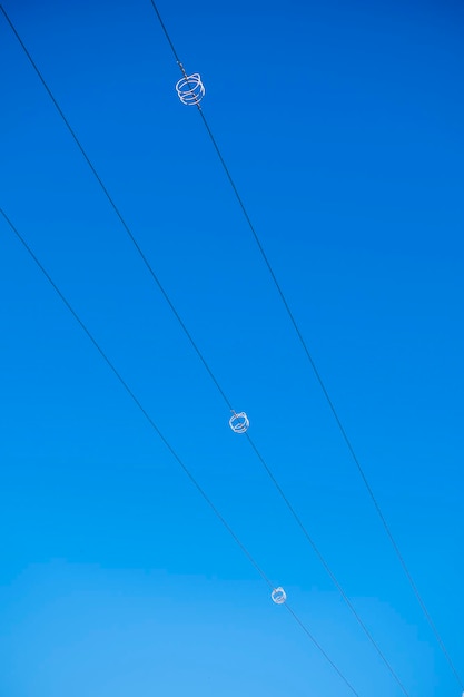 Hoogspanningsdraden met een spiraalvormige spoel tegen de blauwe lucht Gedraaide draad met witte bondage Industrie Elektriciteit