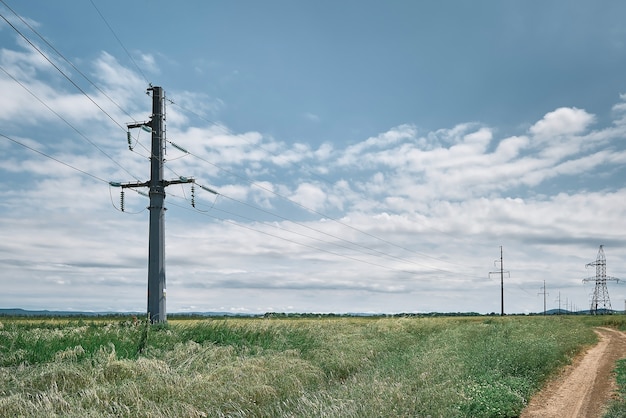 Hoogspanningsleidingen, landschap op een groen veld 's middags, heldere zonnige dag, blauwe lucht met wolken. Energievoorziening voor het stadsleven