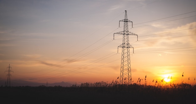 Hoogspanningslijn bij de zonsondergang. Hoogspanningstorens