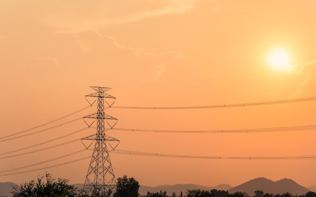 Hoogspanningspaal, Transmissietoren met de zon op rijstveld op het platteland bij zonsondergang