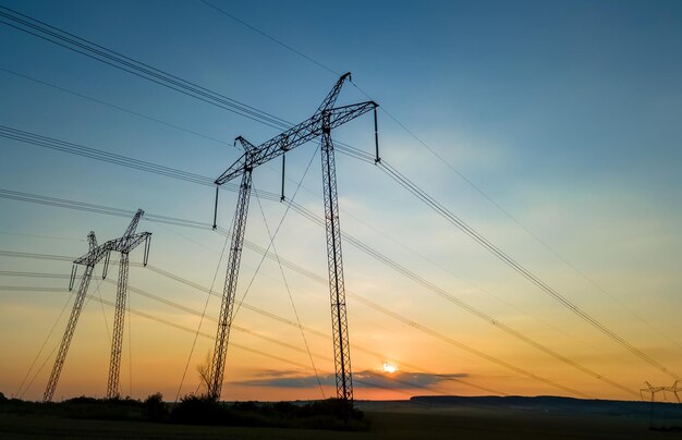 Hoogspanningstorens met elektrische hoogspanningslijnen bij zonsondergang