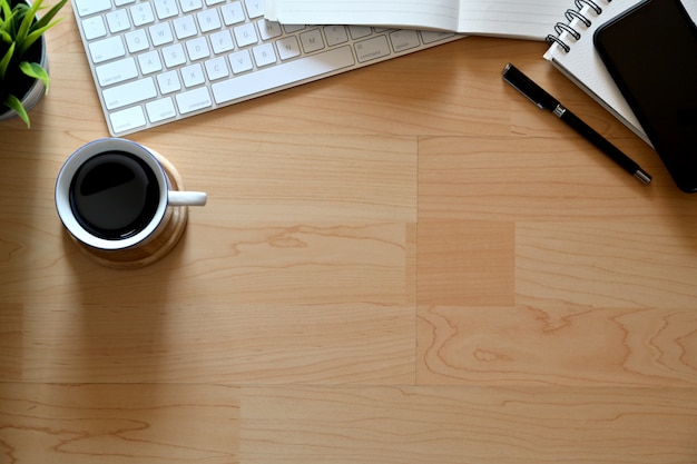 Hoogste bureau houten lijst met kop koffie, notitieboekje, potlood, toetsenbord en exemplaarruimte