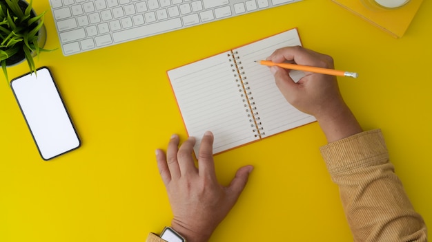 Hoogste mening van de mens die aan zijn project werkt door op notitieboekje in trendy werkplaats te schrijven