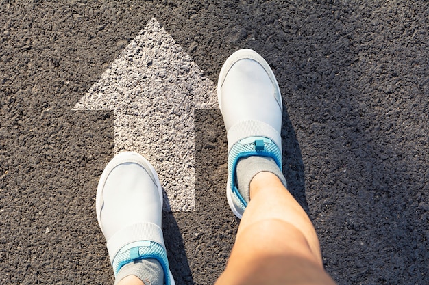 Hoogste mening van de mens die witte schoenen draagt die een manier kiezen duidelijk met witte pijlen