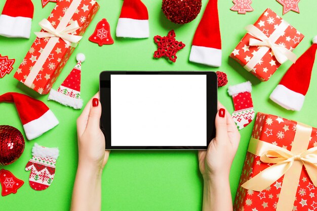 Hoogste mening van de tablet van de vrouwenholding in haar handen op groen gemaakt van Kerstmisdecoratie.