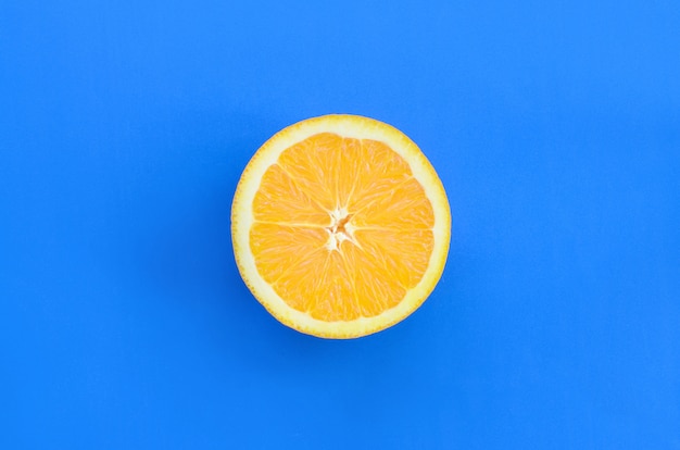 Hoogste mening van een één oranje fruitplak op heldere achtergrond in blauwe kleur. Een verzadigd beeld van de citrustextuur