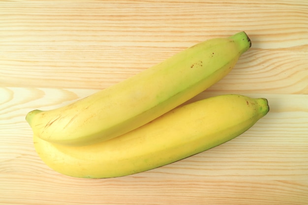 Hoogste Mening van een Paar Heldere Gele Rijpe die Bananen op Houten Achtergrond worden geïsoleerd