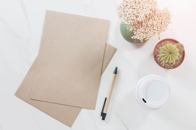 Hoogste mening van envelop, pen, cactus, koffiekop en bloem op witte marmeren lijstachtergrond