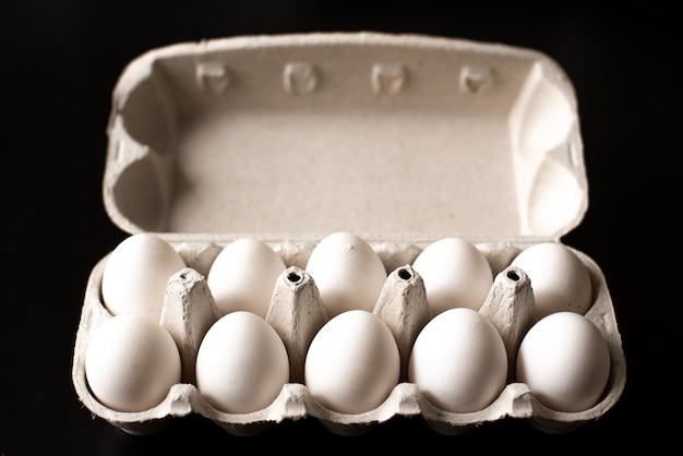Foto hoogste mening van geopende doos met eieren op zwarte achtergrond.