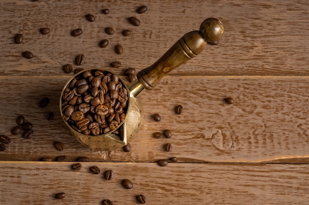 Hoogste mening van verse geroosterde koffiebonen in cezve (traditionele Turkse koffiepot) op houten lijst.