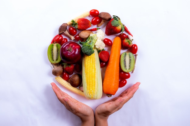 Hoogste mening van vrouwenhand met verse groenten en vruchten op witboek. wereldvoedseldag of vegetarische dag.