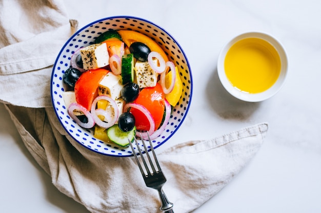 Hoogste menings Griekse salade met olijfolie op marmer.