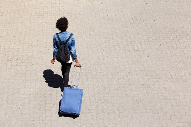 Hoogste menings jonge afro Amerikaanse vrouw die op de straat met bagage lopen