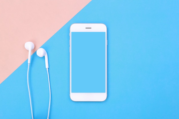 Hoogste menings lege smartphone en oortelefoons op blauwe en roze pastelkleuroppervlakte
