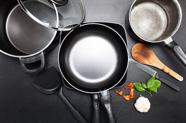 Hoogste meningsbraadpan en pot op het zwarte beeld van de leerlijst voor het koken van achtergrond