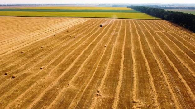 Hooibaal tractor tractor hooi oogsten in balen in het veld op zonnige dag luchtfoto drone view tractor d