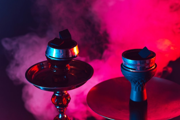 Hookah bowl and coals close up on a black background with smoke