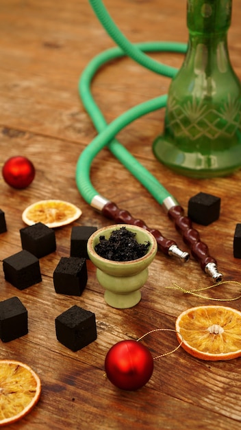 Hookah, charcoal, dry orange slices and Christmas red balls on a wooden table