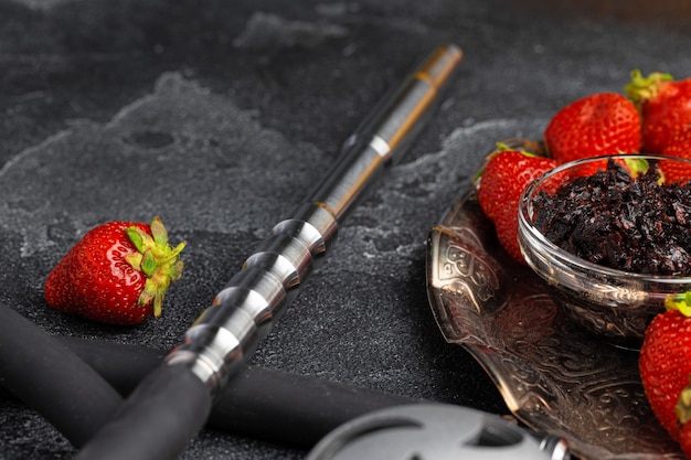 Hookah parts and strawberry on gray surface close up photo