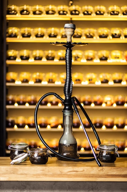 Photo hookah on the water stands on the bar with banks of tobacco with different tastes shisha concept