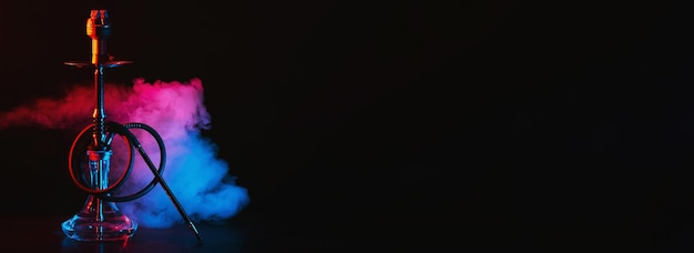 Фото Кальян со стеклянной колбой и металлической миской кальяна с цветным дымом на столе
