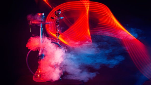 Hookahs with shisha coals in bowls on the table with red and blue neon lights