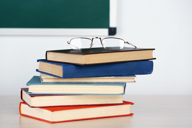 Hoop boeken en glazen op tafel in de klas