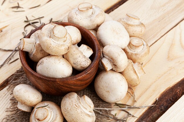 Hoop champignons, champignons in kom op houten tafel, bovenaanzicht