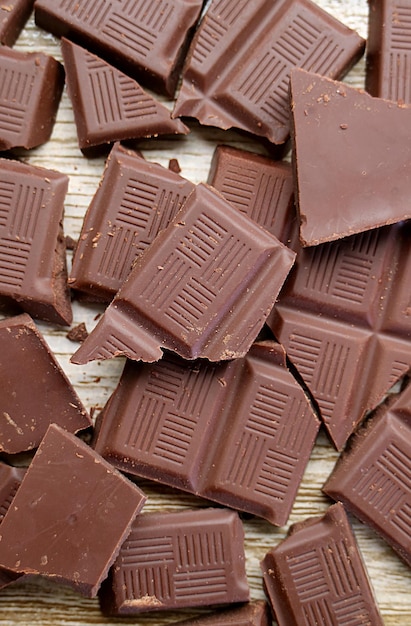 Hoop gebarsten chocoladereep verspreid op houten achtergrond