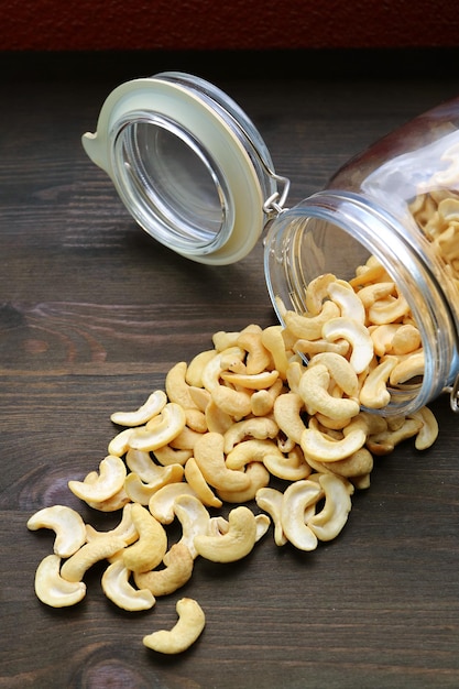 Hoop gedroogde cashewnoten verspreid uit een glazen pot op houten tafel