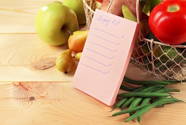 Foto hoop groenten en fruit met boodschappenlijstje op tafel close-up