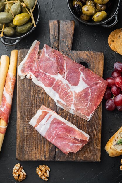 Hoop jamon plakjes set, op zwarte achtergrond, bovenaanzicht