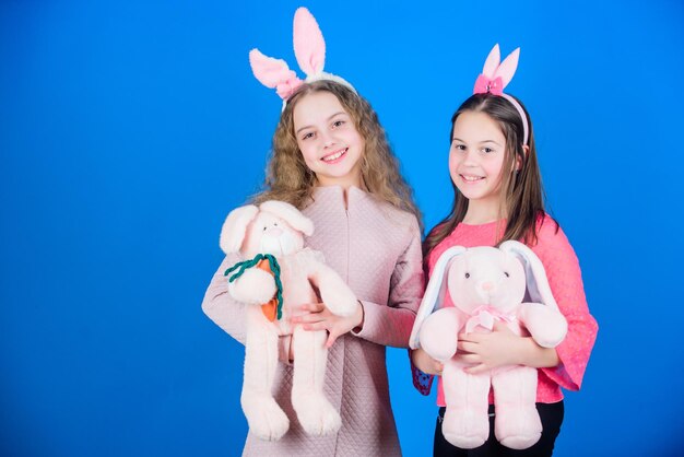 Hoop liefde en vreugdevol leven Vrienden kleine meisjes met konijnenoren vieren Pasen Kinderen met konijntjesspeelgoed op blauwe achtergrond Zusters lachende schattige konijntjeskostuums Verspreid vreugde en geluk rond