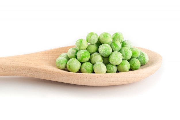 Hoop van bevroren zoete groene erwten in houten lepel geïsoleerd op een witte achtergrond