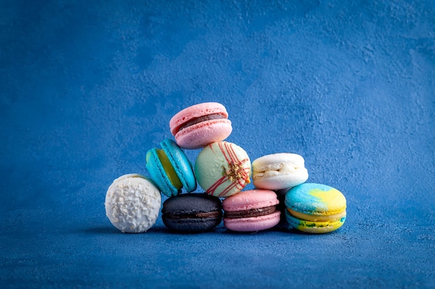 Hoop van gekleurd assortiment van macarons, zoet Frans traditioneel dessert op blauwe achtergrond, close-up horizontale weergave van bovenaf bovenaanzicht kopie ruimte plaats voor tekst