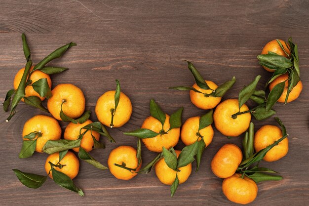 Hoop van mandarijnen met groene bladeren op rustiek hout