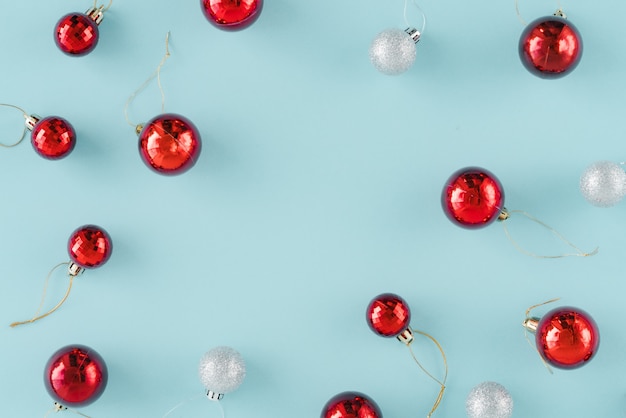 Hoop van rode en zilveren Kerstmisballendecoratie op lichtblauwe achtergrond.