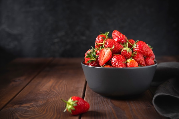 Hoop van verse aardbeien in keramische kom op houten tafel