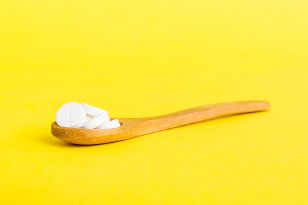 Hoop van witte pillen op gekleurde achtergrond Tabletten verspreid over een tafel Stapel rode zachte gelatinecapsule Vitaminen en voedingssupplementen concept