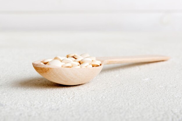 Hoop van witte pillen op gekleurde achtergrond tabletten verspreid over een tafel stapel rode zachte gelatinecapsule vitaminen en voedingssupplementen concept